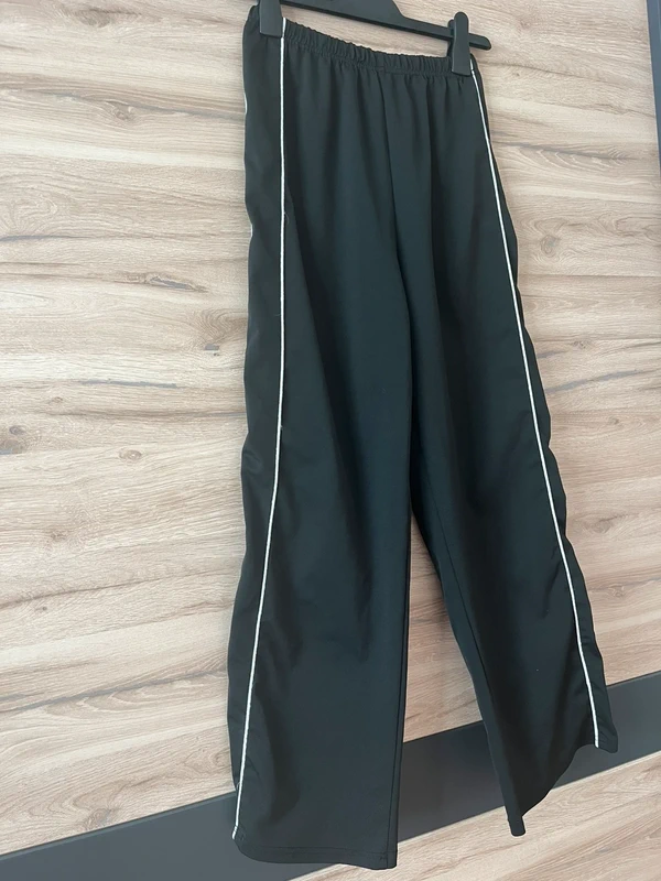 Černé sportovní kalhoty s bočním pruhem — detail